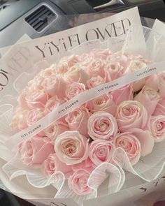 a bouquet of pink roses sitting on top of a car dashboard next to a book