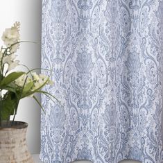 a blue and white shower curtain next to a potted plant