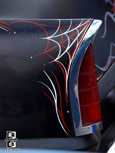 the back end of a black car with red and white designs on it's side