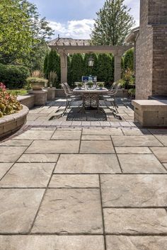 an outdoor dining area with stone patio and pergolated seating areas on both sides