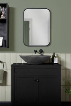 a bathroom with a sink, mirror and shelf on the wall next to green walls