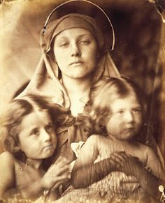 an old black and white photo of a woman with two children on her lap,