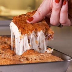 a person is taking a piece of cake from a pan with icing on it