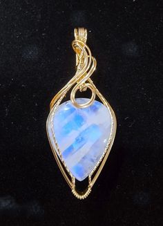 This moonlit beauty is a stunning Rainbow Moonstone with gorgeous adularescence.  A beautiful blue light mysteriously glows from within this gemstone.   The 33 carat natural Moonstone measures 23x26x7mm and is artfully handcrafted in 14K (14/20) yellow gold filled wire.  The pendant measures approximately 2 3/8 inches in length and 1 inch wide.  The bail is generously sized in order to accommodate a variety of chain widths. A handcrafted pendant and a unique and beautiful stone,  it is one of a kind. A gift box is included. Celestial Moonstone Cabochon Jewelry, Celestial Gemstone Jewelry Collectible, Collectible Celestial Gemstone Jewelry, Mystical Iridescent Moonstone Jewelry, Spiritual Moonstone Jewelry For Collectors, Celestial Wire Wrapped Moonstone Jewelry, Blue Cabochon Moonstone Jewelry, Celestial Oval Jewelry With Natural Stones, Celestial Jewelry With Oval Natural Stones