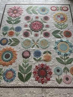 a quilted table runner with flowers and leaves on the border, in various colors