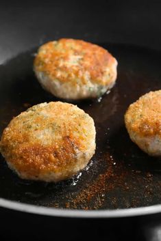 three crab cakes cooking in a frying pan