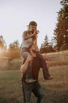 a man carrying a woman on his back in the grass with trees in the background