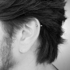 a close up of a person's ear with a piercing on it and long hair