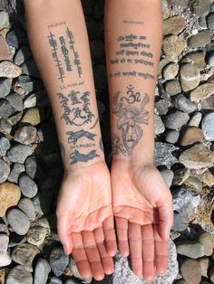 two people with tattoos on their arms are standing in front of some rocks and pebbles