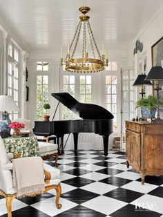 a living room with black and white checkered flooring, chandelier and piano