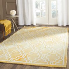 a yellow and white area rug in front of a window with curtains on the outside