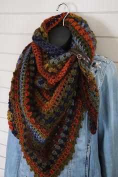 a multicolored crocheted scarf hanging on a coat hanger