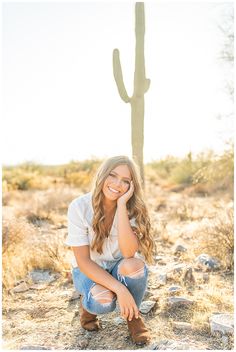 a woman sitting on the ground next to a cactus