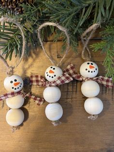 three snowman ornaments hanging from a christmas tree