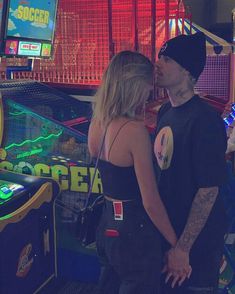 a man and woman standing next to each other in front of a pinball machine