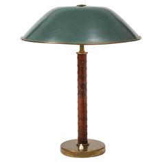 a lamp that is on top of a wooden base and has a green shade over it