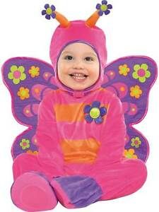 a baby in a pink and purple butterfly costume sitting on the ground with her legs crossed