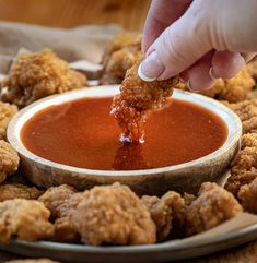 a person dipping sauce into some fried food