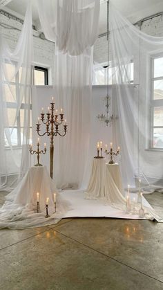 a room filled with lots of white curtains and candles