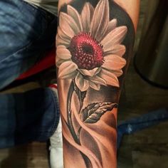 a person with a tattoo on their arm holding a red and white flower in front of them