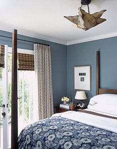 a bed room with a neatly made bed and blue walls