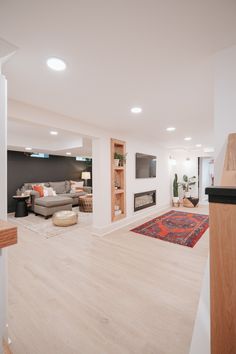 an empty living room with white walls and wood flooring on the far wall is a fireplace