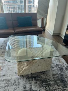 a living room with couches and a glass table in front of a large window