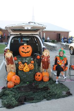 two children sitting on chairs in the back of a van decorated with pumpkins