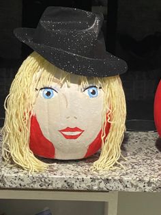 a pumpkin with a face painted on it and a hat sitting next to an apple