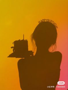 the silhouette of a woman with a birthday cake in her hand, against an orange and yellow background