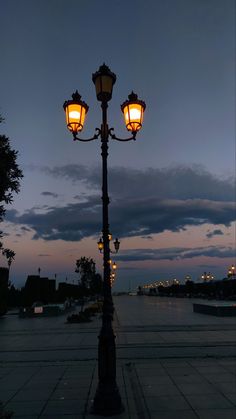 a street light sitting on the side of a road next to a lake at night