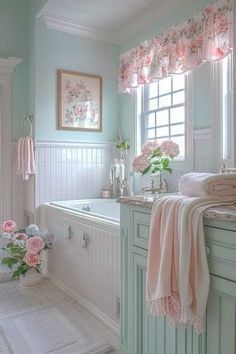 a white bathroom with pink flowers on the window sill and towels hanging over the bathtub