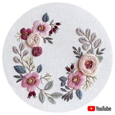 a white circle with pink flowers and green leaves on the center is embroidered onto it