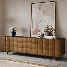 a wooden cabinet with flowers and pictures on it next to a rug in a room