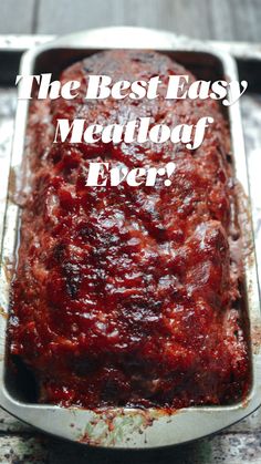 a meatloaf in a metal pan with sauce on it sitting on a table