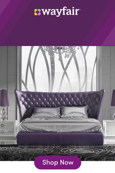 a purple bed sitting in front of a window next to two lamps and a table