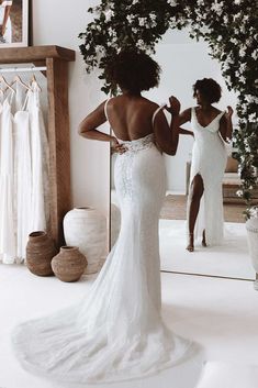 a woman standing in front of a mirror wearing a wedding dress and looking at herself in the mirror