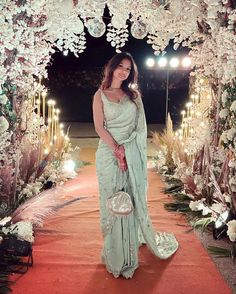 a woman in a long dress standing under an archway with flowers and candles on it