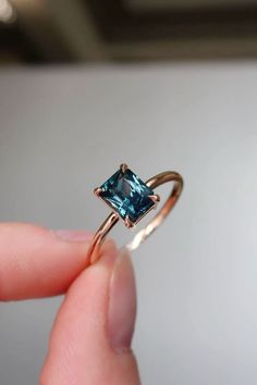 a person holding a ring with a blue stone in it