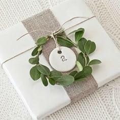 a gift wrapped in burlap with greenery and a tag that says i love you