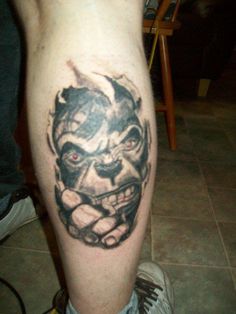 a man's leg with a tattoo on it that has a clown face and teeth