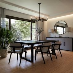 a dining room table with four chairs and a large mirror on the wall above it