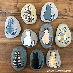 rocks with cats painted on them sitting on a wooden floor