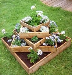 several wooden boxes filled with plants and flowers on the grass in a garden area next to a deck