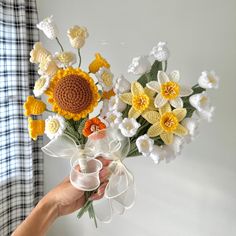 a person holding a bouquet of crocheted flowers in their hand with the sunflowers on top