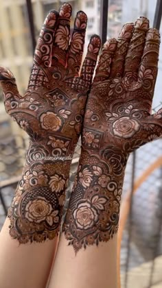 two hands with henna tattoos on them, one is showing off the intricate design