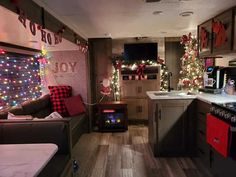 a living room filled with furniture and christmas lights on the wall next to a kitchen