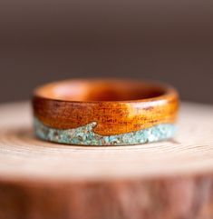 a wooden ring sitting on top of a piece of wood with blue and brown inlays