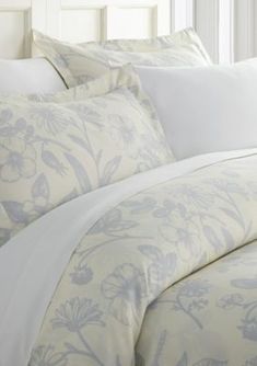 a bed with white sheets and blue flowers on it