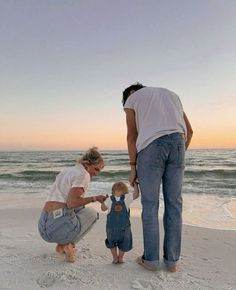 a woman and two children on the beach with an adult holding a child's hand